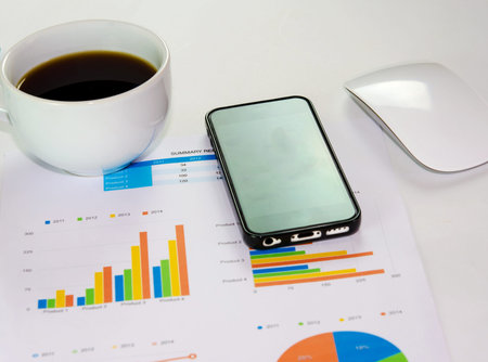 smartphone and some charts and graphs on a desktop.