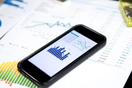 Smart phone and chart on the table.の写真素材