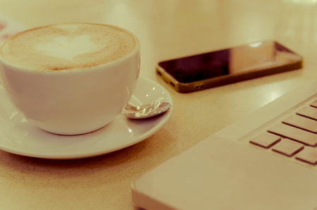 Coffee cup and smart phone on table - vintage style effect picture