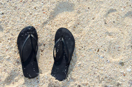 Black slippers on tropical beach in holiday.の写真素材