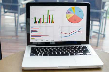 Computer with a business graph on screen on the table