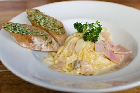 Spaghetti Carbonara with ham and mushroom  with garlic bread.の写真素材