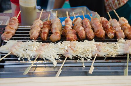 Bacon wrap grilled sausage And golden mushrooms grilled on the stove.の写真素材
