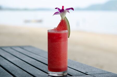 Water melon spinning on a wooden table, the background is the beach.の写真素材