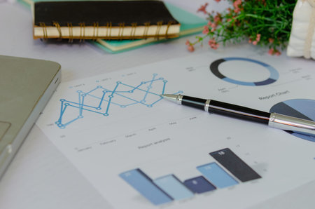 Business graph research and pen with computer laptop on desk.