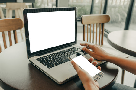 women's hands holding mobile phone and computer laptop screen for your advertising text messageの写真素材