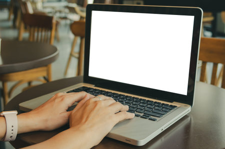 Woman's hands using computer laptop with blank screen on desk.の写真素材