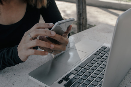 woman use smartphone and computer laptop on deskの写真素材