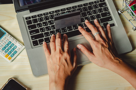 Hands holding a credit card and using a laptop computer on the tableの写真素材