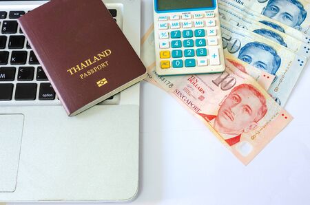 Fifty dollars and ten dollars Singapore and passports and calculators with computer laptop on a white backgroundの写真素材