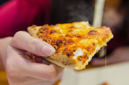 A young girl holds a ham and cheese pizza in hand.の写真素材