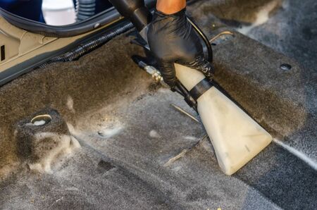Washing the carpet of the car by a vacuum cleaner on the carpet.の写真素材