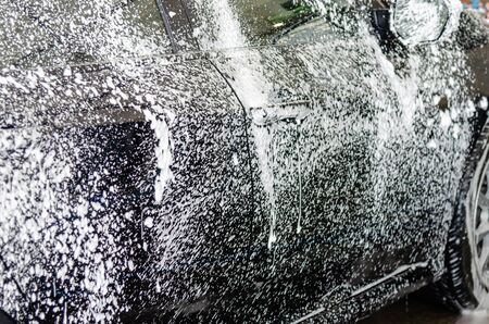 Cleaning black cars. Wash the car at the car wash station with foam bubbles.の写真素材