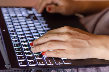Close-up of a woman working on a notebook and typing on a computer keyboard