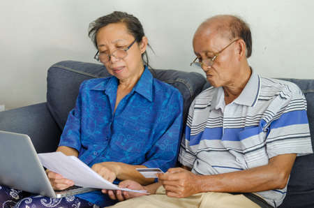 Seniors woman and man looking business documents computer and credit card.の写真素材