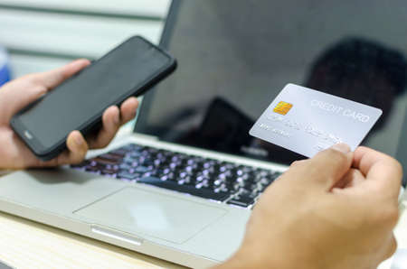 Man Shopping Online Using Laptop With Credit Card.Hands holding credit card and smartphone.の写真素材