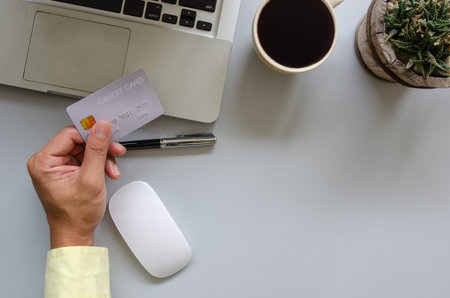 Top view man holding a credit card and on the desk. Laptop computer Notepad and pen.Online shopping business, pay by credit cardの写真素材