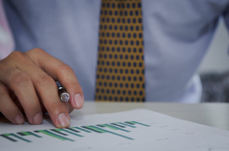 Business man holding a pen, business documents, reports, graphs and charts of financial statements...