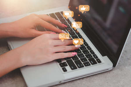 woman uses computer laptop social media for internet marketing. Concept of business technology with notification icons of like, message, email, commentの写真素材