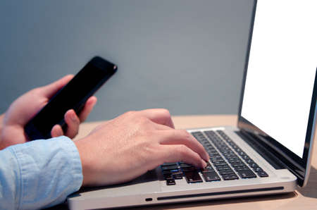 businessman hand typing computer at desk with blank screen mock upの写真素材