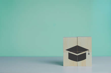Wooden cube with graduation cap icon.Education concept. Graduation day success on background copy space.の写真素材