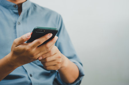 Close up of a man using mobile smart phone searching internet, sending sms, using text messenger or online banking.Copy space.の写真素材