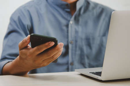 man using mobile smart phone and computer laptop searching internet, sending sms, using text messenger or online banking.の写真素材
