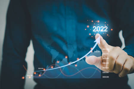 businessman touches arrows and graphs on a virtual screen. Financial Business Planning 2022 Marketing Goals concept.の写真素材