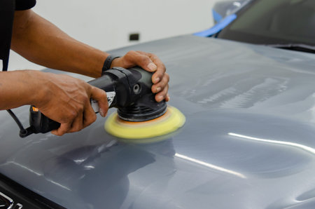 Man holding tool polish mechanic auto repair detailing hood car scratch maintenance in garage...