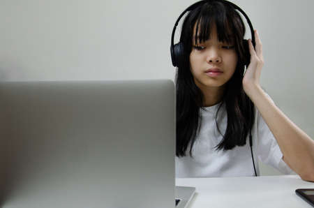 girl wearing headphones studying online with computer laptop and listen to relaxing music or play internet social media at home.の写真素材