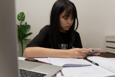 Asian student girl is writing homework and reading book at deskの写真素材