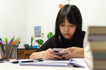 Asian young girl use a mobile smart phone to study education online at home.の写真素材