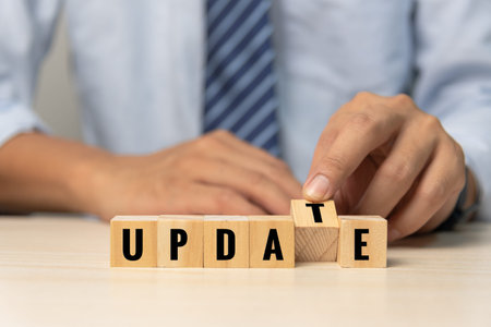Businessman hand holding wood cube block text update on desk concept.の写真素材
