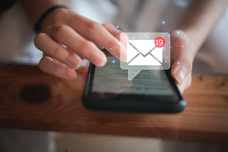 woman holding hand touchscreen smartphone and checking email icon online or sending mail to partner and customer on web with virtual interface technology concept.の写真素材