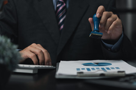 Man stamping approval of work finance banking or investment marketing documents on desk.