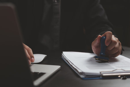 Man stamping approval of work finance banking or investment marketing documents on desk.の写真素材