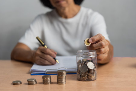 woman saving money with putting coins in glass, finance and accounting concept.の写真素材