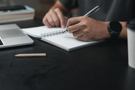 man hands with pen writing on notebook in the office.learning, education and work.writes goals, plans, make to do and wish list on desk.の写真素材