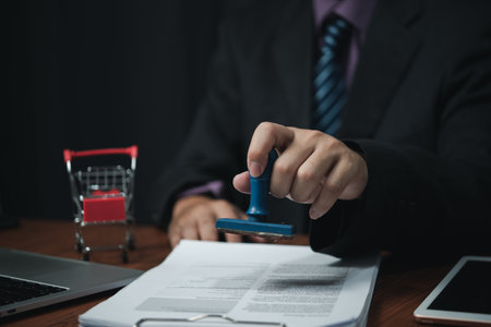Man hand stamping approval signing on document or paperwork contract at desk.の写真素材