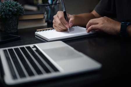 Man hand writing on notebook with computer laptop.Business planning, E learning , journal concept.の写真素材