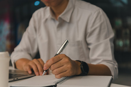 man hands with pen writing on notebook in the office.learning, education and work.writes goals, plans, make to do and wish list on desk.の写真素材