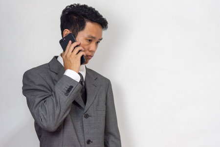 asian businessman looking at mobile phone stressed at work and worriedの写真素材