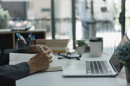 Online Learning at the Workplace laptop computer. taking notes in a notebook while listening to a lecture or engaging in interactive activities.の写真素材