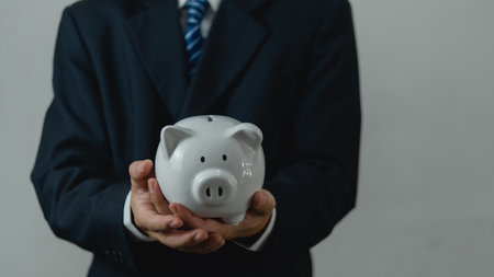 Businessman in suit is holding piggy bank.financial investments and savings money, management and accounting concept.の写真素材