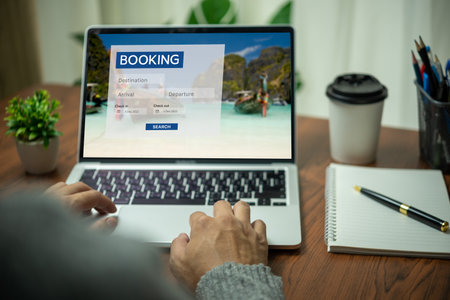 Online booking platform on a laptop computer by a person. Man use websites to search for accommodation, hotels and airlines for their vacation trips or buy tours on the Internet.の写真素材