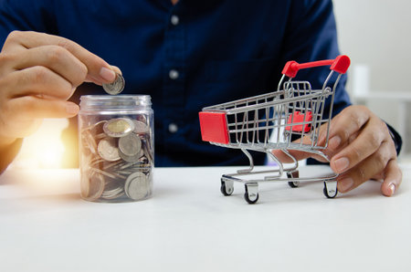 businessman holding coin saving money in jug glass and cart concept. Business finance investment ,accounting , tax concept.の写真素材