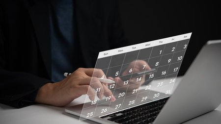 Businessperson planning schedule with digital calendar on laptop. time management, monthly scheduling, productivity tracking. Professional workspace, strategic efficiency, futuristic technology.の写真素材