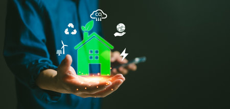 Green smart home hologram in hand, surrounded by eco-friendly icons. Promotes sustainability and renewable energy. Ideal for environmental campaigns, technology, and innovation.の写真素材