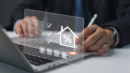 Businessman using laptop with holographic interface, displaying finance icons. Represents digital finance, innovation. Suitable for tech, financial services.の写真素材