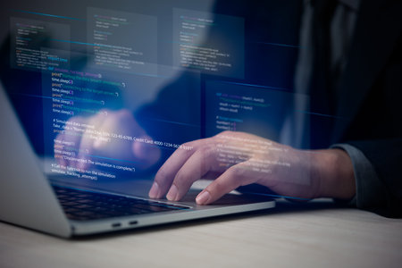 Hands typing on laptop with programming code on screen, representing software development. Perfect...
